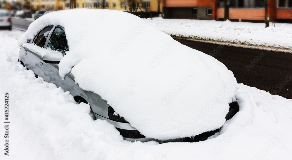 A snowy car on the street in winter A snowy car on the street in winter
