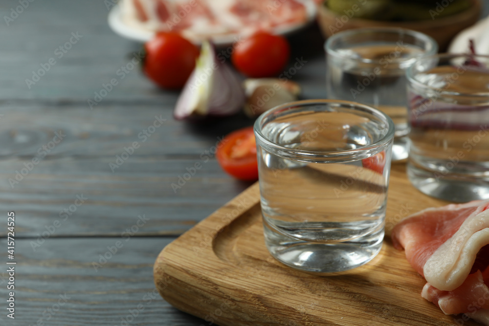 Shots of vodka and tasty snacks on gray wooden background Shots of vodka and tasty snacks on gray wooden background
