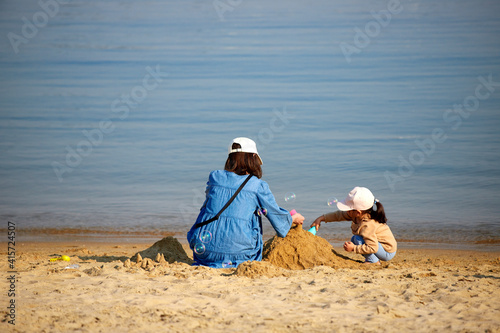 初夏の海で砂遊びしている親子の姿