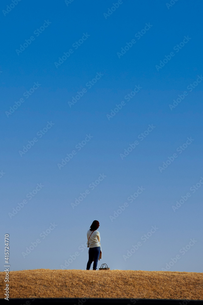綺麗な青空と公園で散歩している若い女性の姿