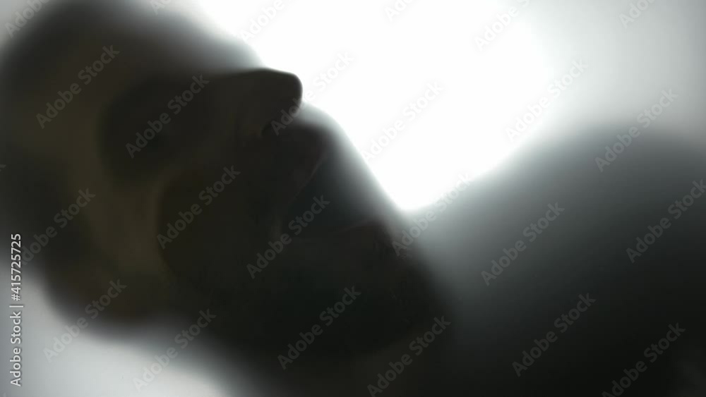 Silhouette of Disturbing Man Looking at Camera Through Translucent Glass Silhouette of Disturbing Man Looking at Camera Through Translucent Glass