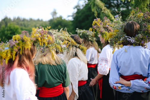 Group of ukrainian girls in embroidered shirts from the back in a wreath of flowers, wildflowers at the celebration of a traditional Slavic holiday Ivana Kupala