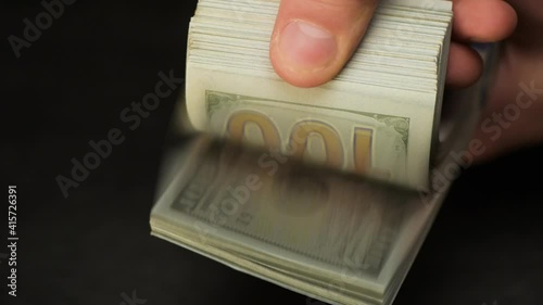 Hands are counting money. One hundred US dollar bills.