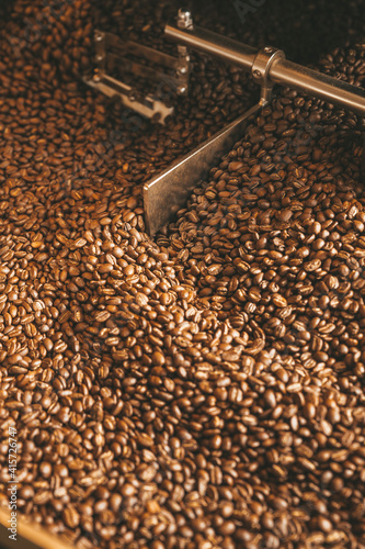 Foto The freshly roasted coffee beans from a large coffee roaster being poured into the cooling cylinder