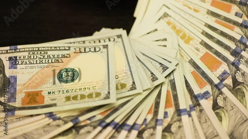 One hundred US dollar banknotes are unfolded by a fan.