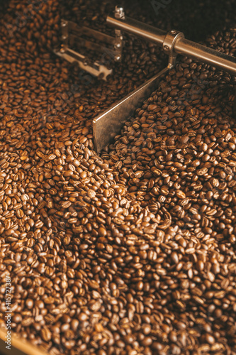 The freshly roasted coffee beans from a large coffee roaster being poured into the cooling cylinder. Motion blur on the beans