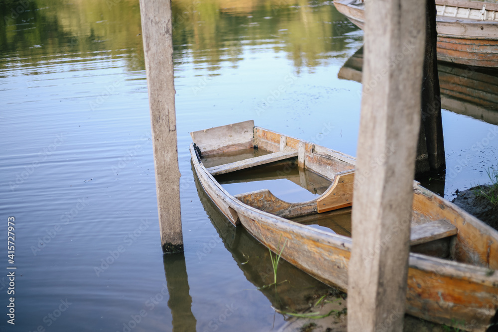 Half sunken wooden boat is moored to the shore Half sunken wooden boat is moored to the shore