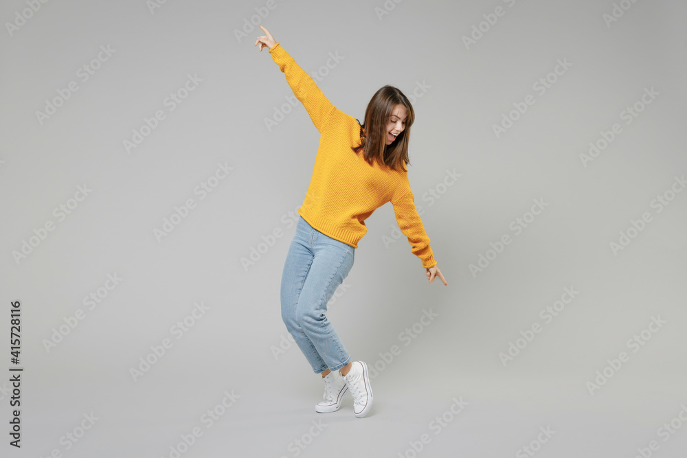 © ViDi Studio - Full length of young relaxed positive student caucasian happy satisfied woman 20s wearing knitted yellow sweater leaning over with outstretched isolated on grey color background studio portrait.. © ViDi Studio - Full length of young relaxed positive student caucasian happy satisfied woman 20s wearing knitted yellow sweater leaning over with outstretched isolated on grey color background studio portrait..
