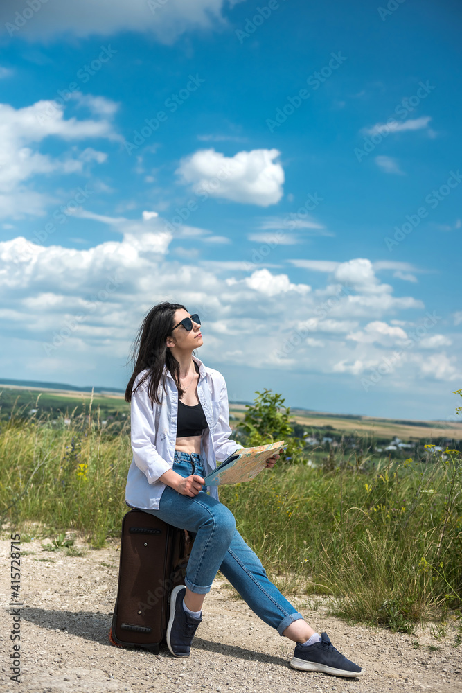 Woman tourist sitting on her luggage and look the map for choose best away Woman tourist sitting on her luggage and look the map for choose best away