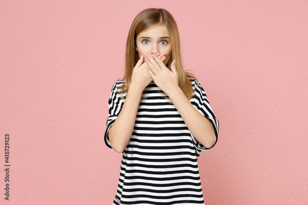 Little blonde shocked surprised kid nice girl 12-13 years old wear striped oversized t-shirt cover mouth with hands looking camera isolated on pink background children. Childhood lifestyle concept.