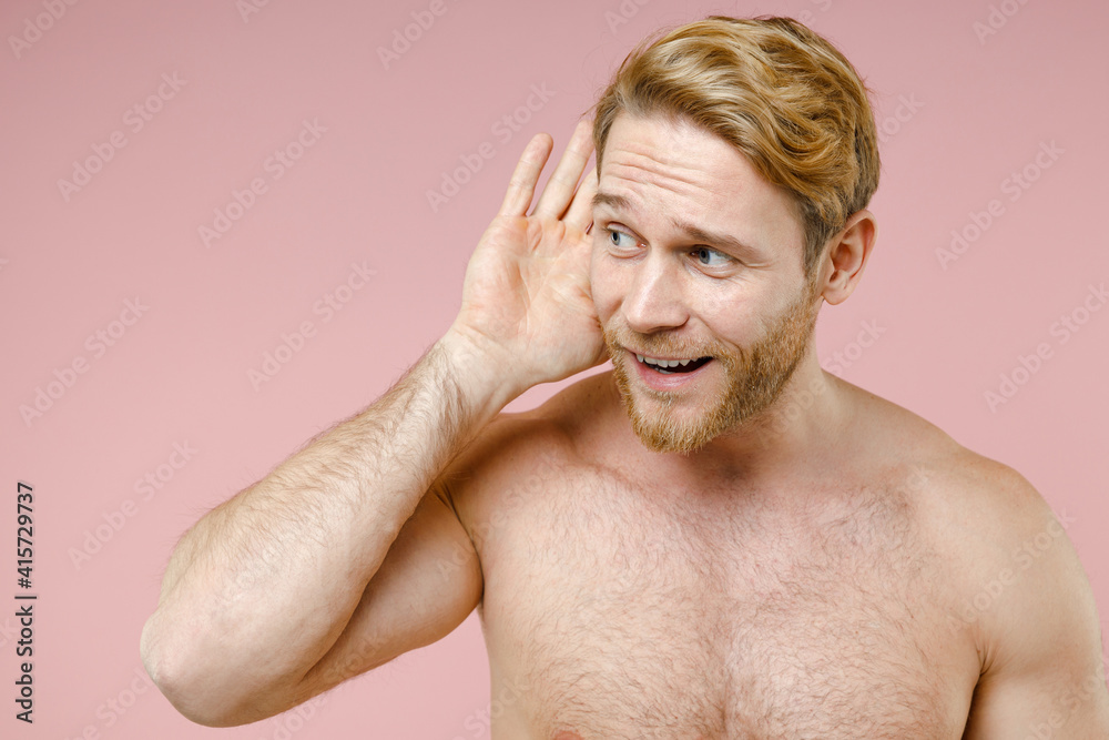 Obraz premium Curious bearded naked young man 20s perfect skin try to hear you overhear listen intently looking aside isolated on pink background studio portrait. Skin care healthcare cosmetic procedures concept.