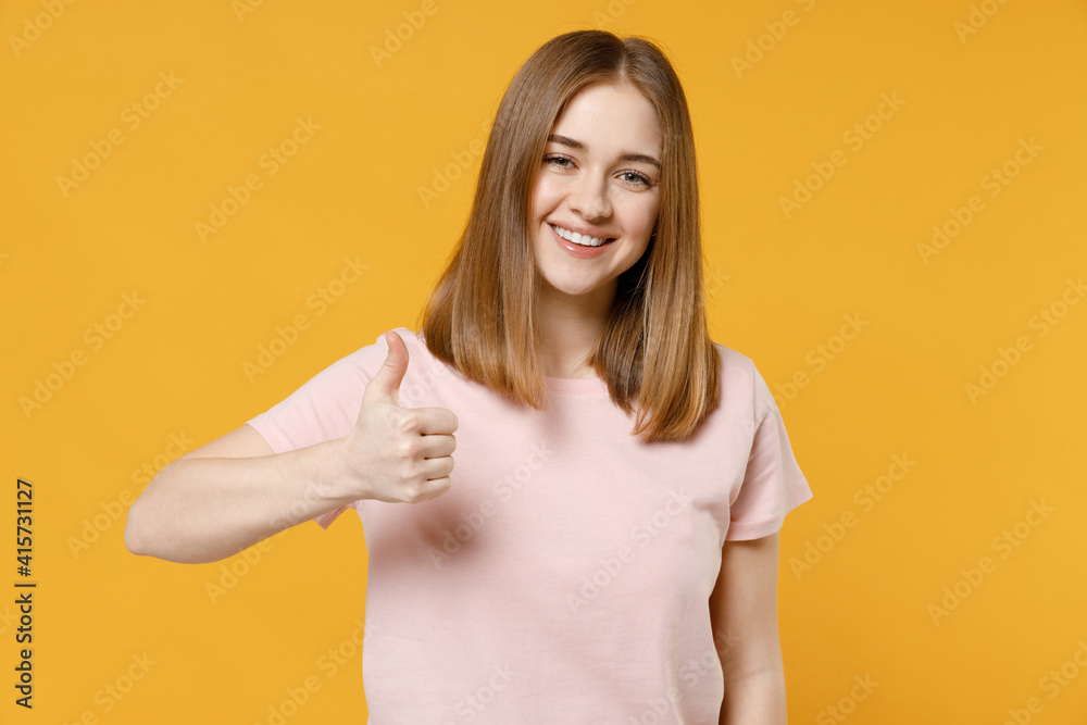 Young smiling overjoyed happy excited positive satisfied woman 20s with nude make up wearing casual basic pastel pink t-shirt show thumb up like gesture isolated on yellow background studio portrait Young smiling overjoyed happy excited positive satisfied woman 20s with nude make up wearing casual basic pastel pink t-shirt show thumb up like gesture isolated on yellow background studio portrait