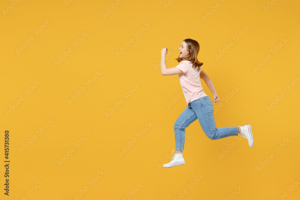 Full length side profile view of young sportive energetic caucasian hurrying up woman 20s wearing basic pastel pink t-shirt jumping high run fast isolated on yellow color background studio portrait.