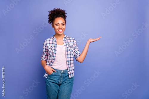 Photo of charming shiny young woman wear plaid shirt holding arm empty space isolated violet color background photo