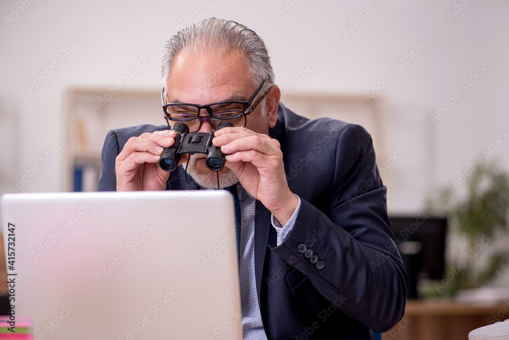 Old male employee auditor wearing many glasses at workplace Old male employee auditor wearing many glasses at workplace