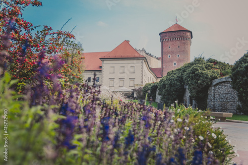 Wawel Senator Tower with castle, green lawns, ivy on the wall, umbrellas and flowers on sunny day. Part of the Wawel royal Castle in Krakow, Poland. Built at the behest of King Casimir III the Great. © pijav4uk