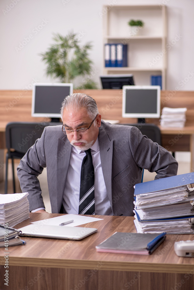 Old male employee unhappy with excessive work in the office Old male employee unhappy with excessive work in the office