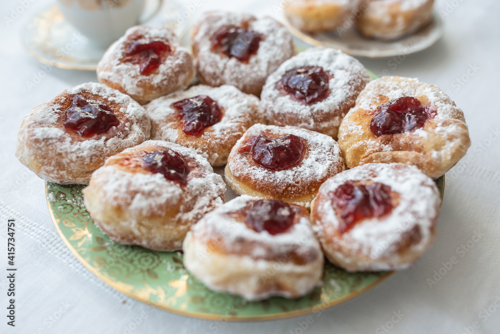A plate of donuts filled with jam and coated in sugar
