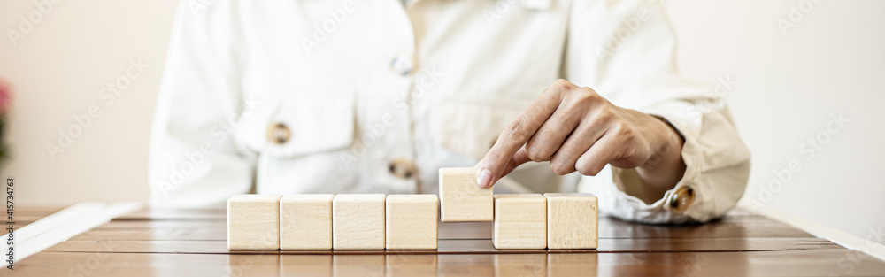 The business woman grasped the rectangular wooden blocks in a row, the square wooden blocks arranged on the table by the businesswoman. The business woman grasped the rectangular wooden blocks in a row, the square wooden blocks arranged on the table by the businesswoman.