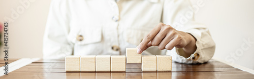 The business woman grasped the rectangular wooden blocks in a row, the square wooden blocks arranged on the table by the businesswoman.