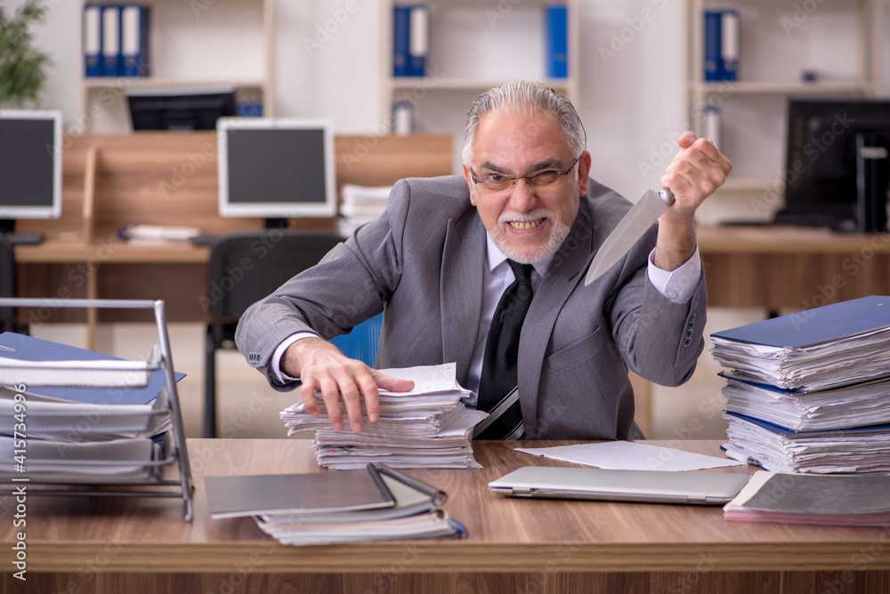 Old male employee unhappy with excessive work in the office Old male employee unhappy with excessive work in the office
