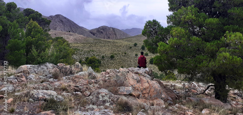 boy standing looking at the landscape after climbing a mountain 