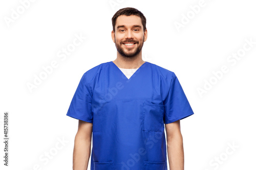 healthcare, profession and medicine concept - happy smiling doctor or male nurse in blue uniform over white background © Syda Productions