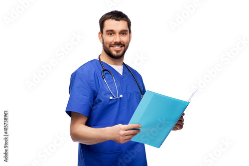 healthcare, profession and medicine concept - happy smiling doctor or male nurse in blue uniform reading medical report in folder over white background