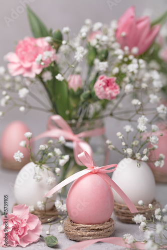 Happy easter! Painted pink eggs with pink flowers - tulips and carnations. Selective focus. 