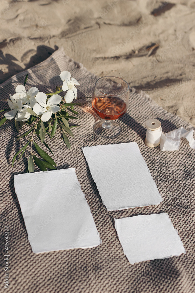 Summer wedding stationery mockups set. Vacation still life. Picnic on golden Mediterranean beach sand. Glass of red wine, white oleander flowers and olive branches on beige towel. Top view, vertical. Summer wedding stationery mockups set. Vacation still life. Picnic on golden Mediterranean beach sand. Glass of red wine, white oleander flowers and olive branches on beige towel. Top view, vertical.