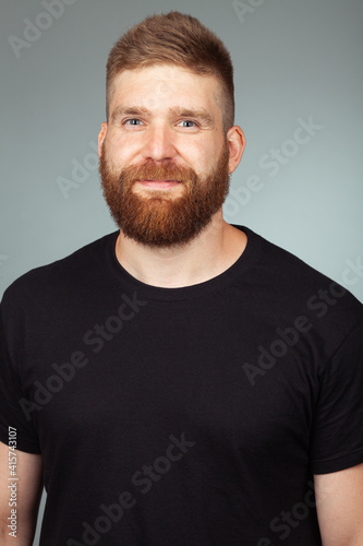 Portrait of sweet charismatic muscular 30-year-old man with red hair posing over light gray background. Perfect haircut. Rocker, biker, hipster style. Studio shot