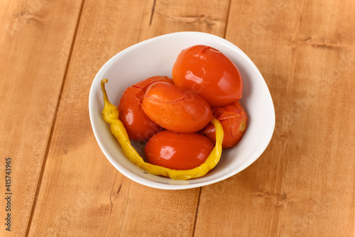 Pickled red tomatoes with chilli in a plate.