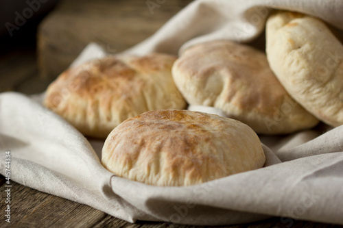 Three homemade whole-grain pita bread on a linen towel.