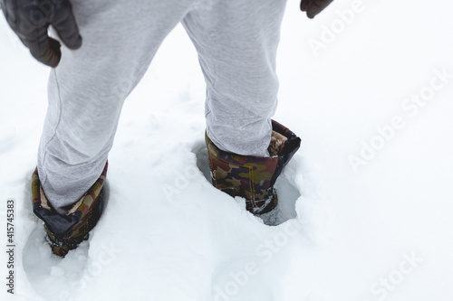 man in boots stands in deep snow