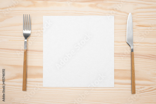 Mockup Blank card and cutlery. Knife and fork with white paper for menu or recipe text. Flat lay with mockup food menu on rustic wooden table