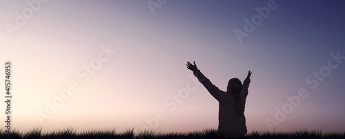 Silhouette of a girl raising arms to sky evening