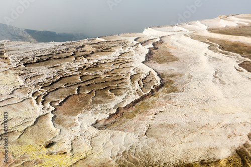 Lacy white travertine formations at hot springs of cotton castle of Pamukkale on sunny day, Turkey photo