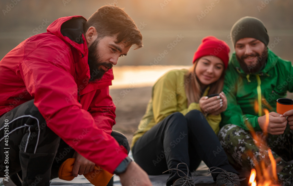 Group of friends warming up near campfire Group of friends warming up near campfire