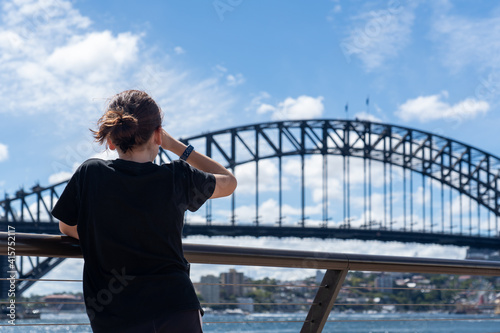 Fototapeta Naklejka Na Ścianę i Meble -  Young girl from behind in the city looking at the view of the Sydney Harbour Bridge