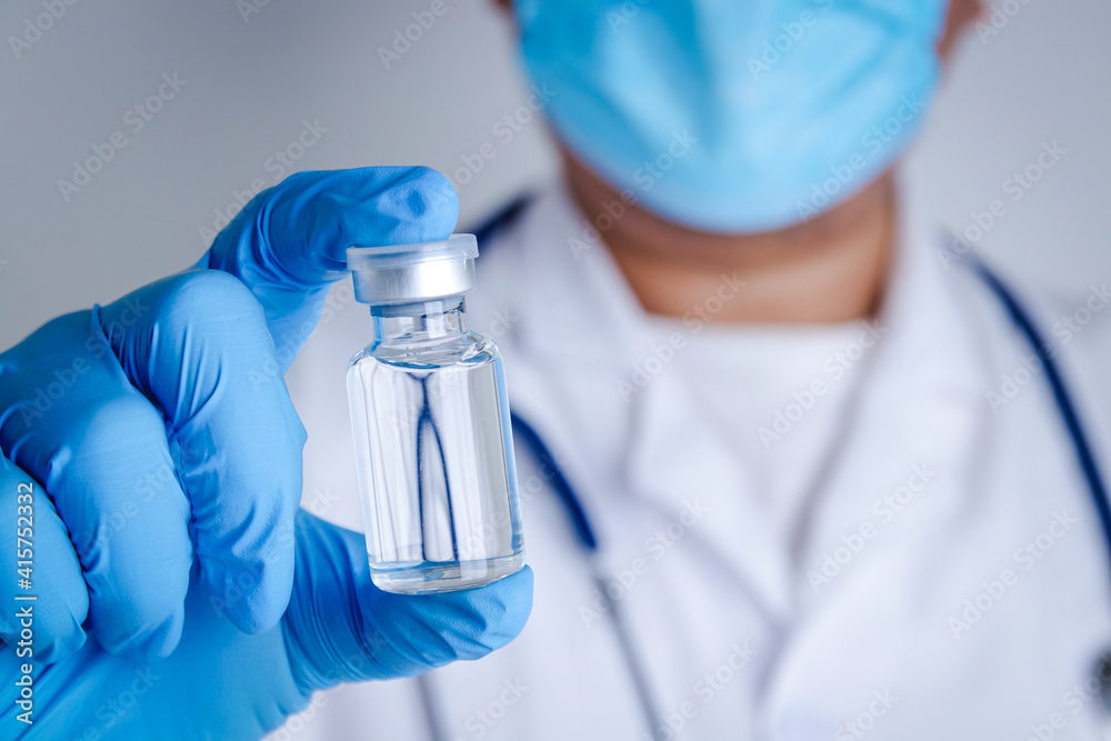 Doctor or researcher Wear blue gloves, work in the laboratory. Pick up a liquid vaccine bottle to treat the coronavirus Or COVID-19. Concept hospital medical services Doctor or researcher Wear blue gloves, work in the laboratory. Pick up a liquid vaccine bottle to treat the coronavirus Or COVID-19. Concept hospital medical services