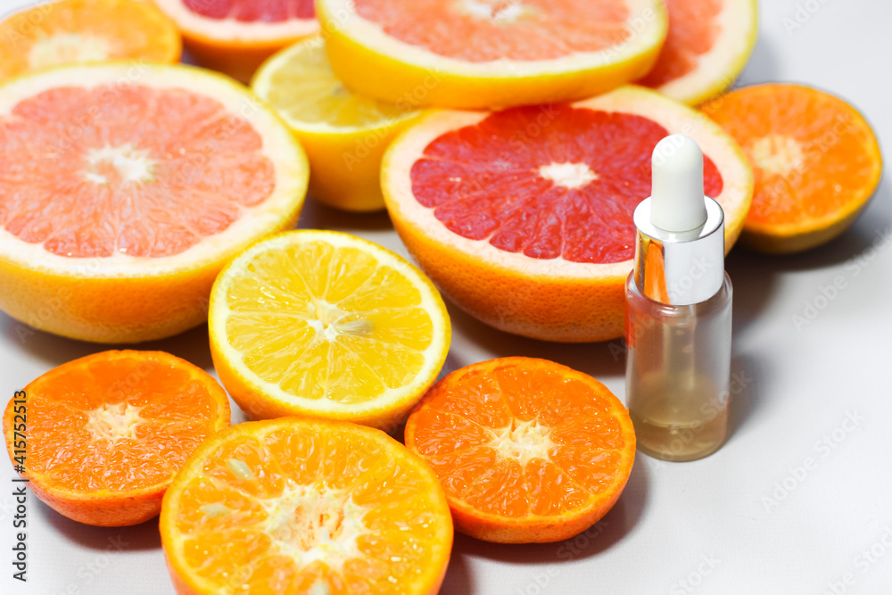 Face serum with vitamin c with different citrus fruits on a white background. Face serum with vitamin c with different citrus fruits on a white background.