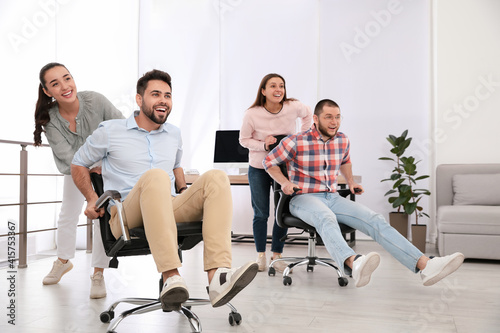 Fototapeta Naklejka Na Ścianę i Meble -  Happy office employees riding chairs at workplace