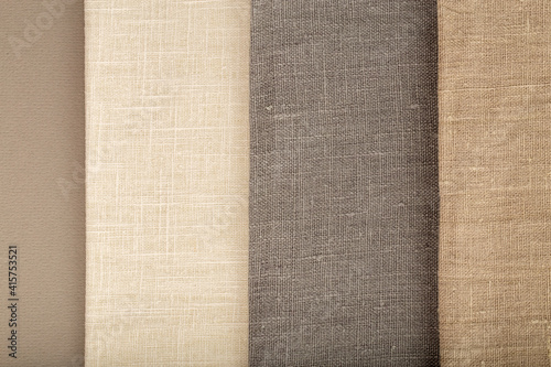 Flat linen fabric on a grey textured surface - off-white, grey, and beige linen.