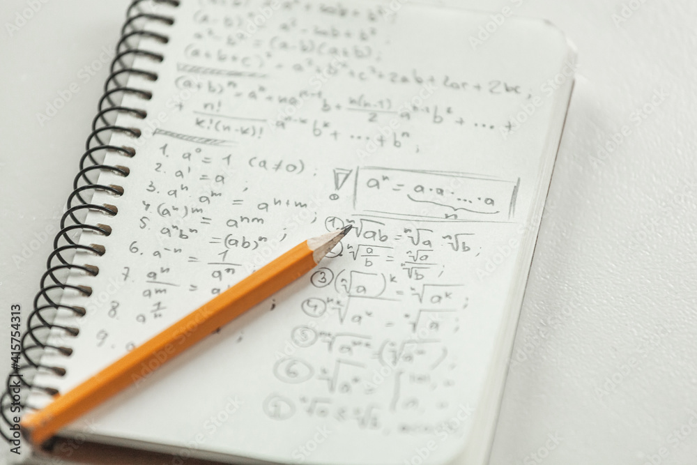 Math formulas are written in pencil on a piece of paper, math problems