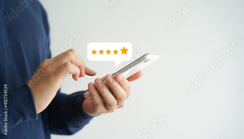 close up on customer man hand pressing on smartphone screen with gold five star rating feedback icon and press level three rank (good) for give score point to review the service business concept	 photo