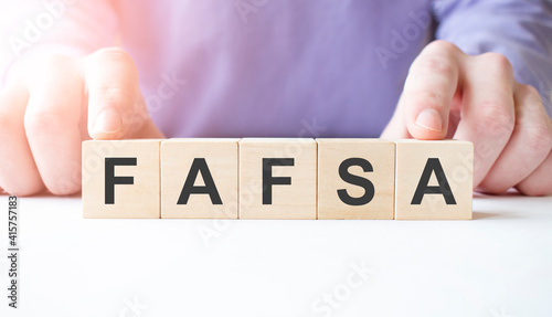 Businessman hand holding wooden cube block with FAFSA business word on table background. Mission, Vision and core values concept photo