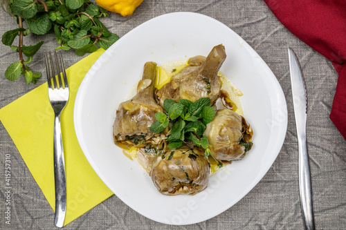 Roman-style artichokes with mint. Traditional Italian cuisine dish. Artichokes alla Romana. Flat lay.