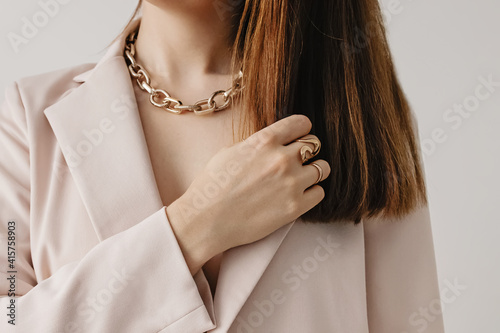 Slika na platnu Woman in light beige jacket wearing golden chain necklace.