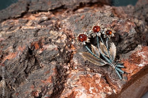 Decoration of amber and bronze in the form of a flower on a wooden background