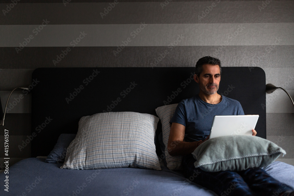 Fototapeta premium Man working in bed with a digital tablet